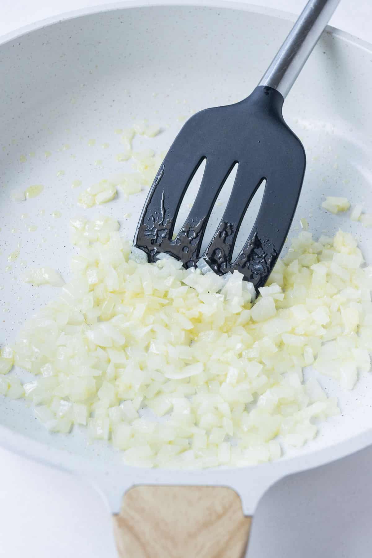 Diced onions are sautéed in a skillet.