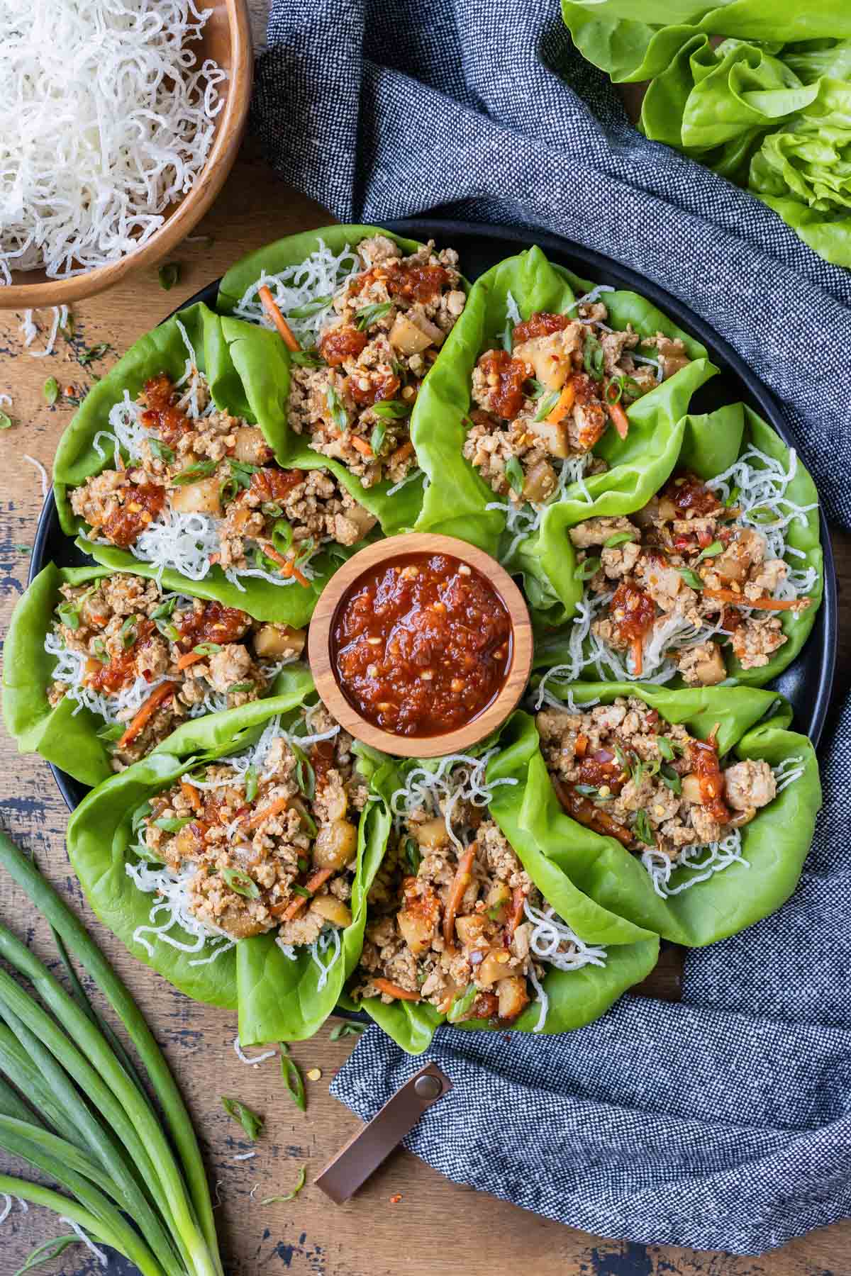 Ground chicken lettuce wraps are on a plate to be served with crispy rice noodles.