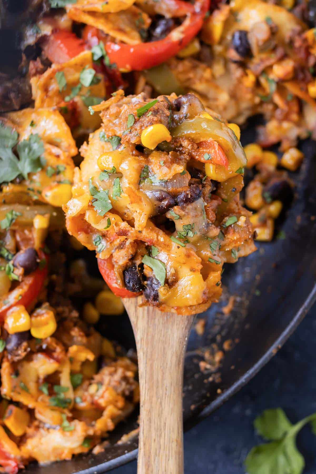 A wooden spoon serves up some beef taco skillet from a cast iron pan.