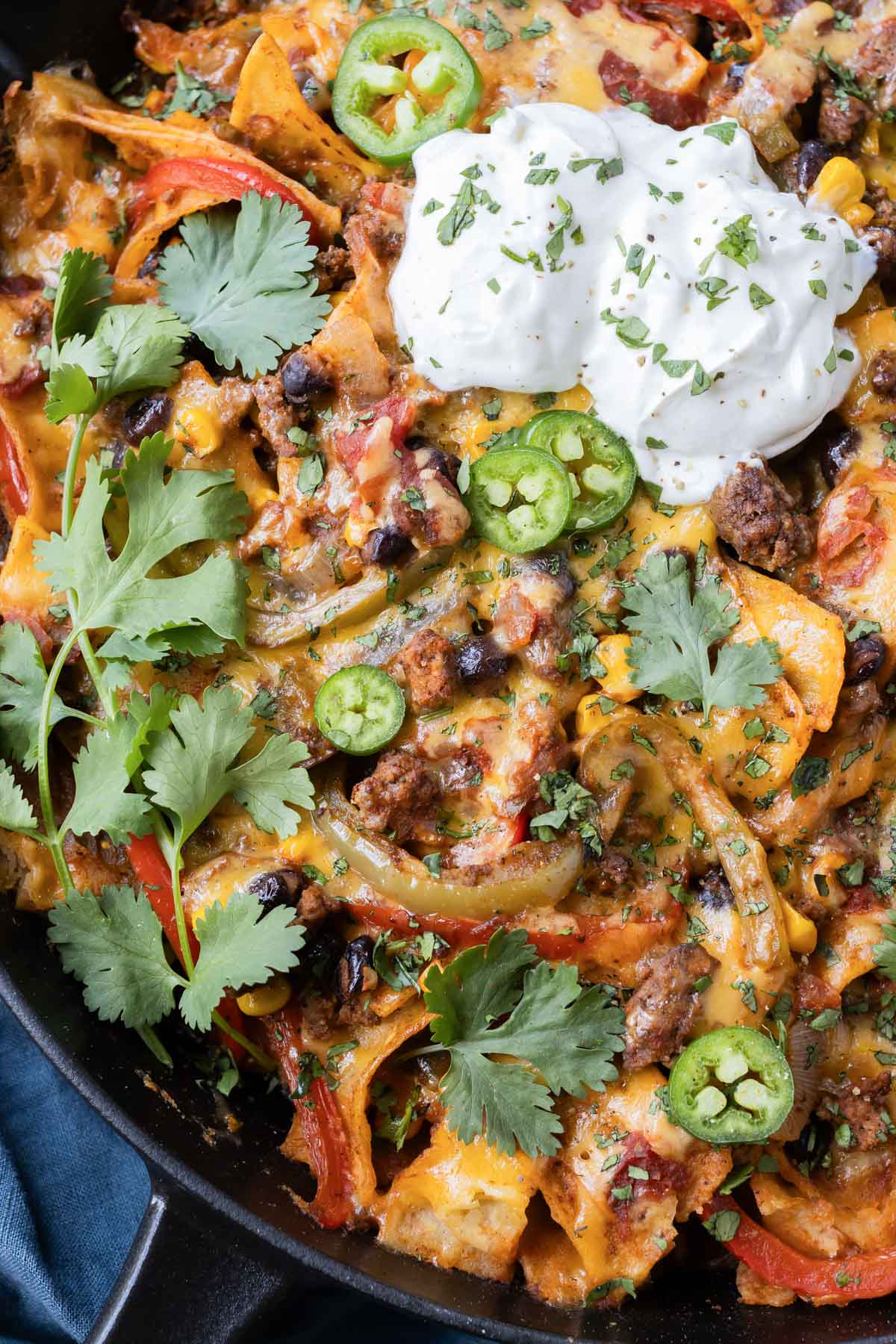 A quick and easy beef taco skillet recipe is served in one-pan with sour cream and cilantro.