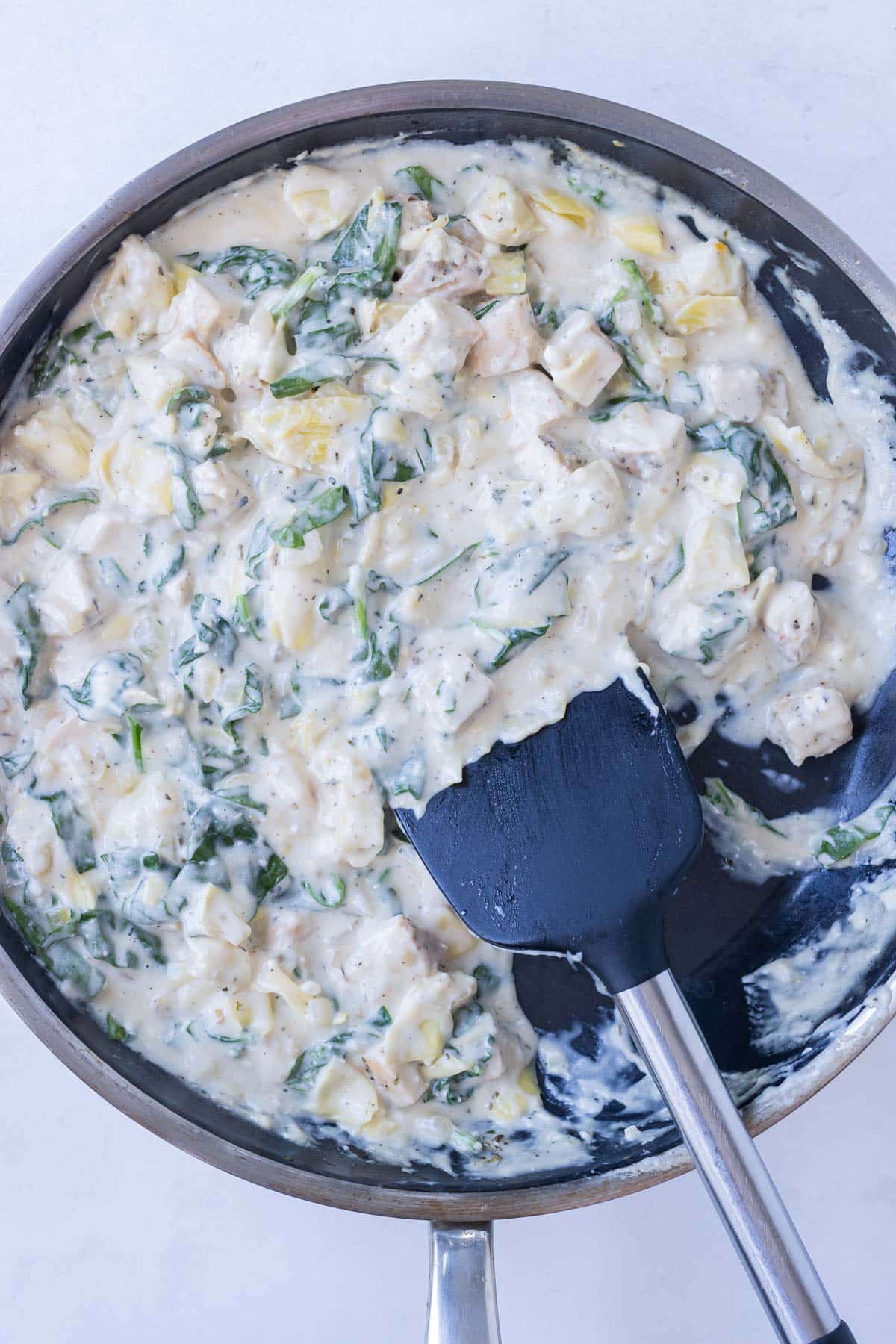 The cooked chicken along with spinach and artichokes are added to the sauce.