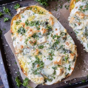 A baked spaghetti squash is stuffed with spinach, artichoke, and chicken with a creamy cheese sauce.