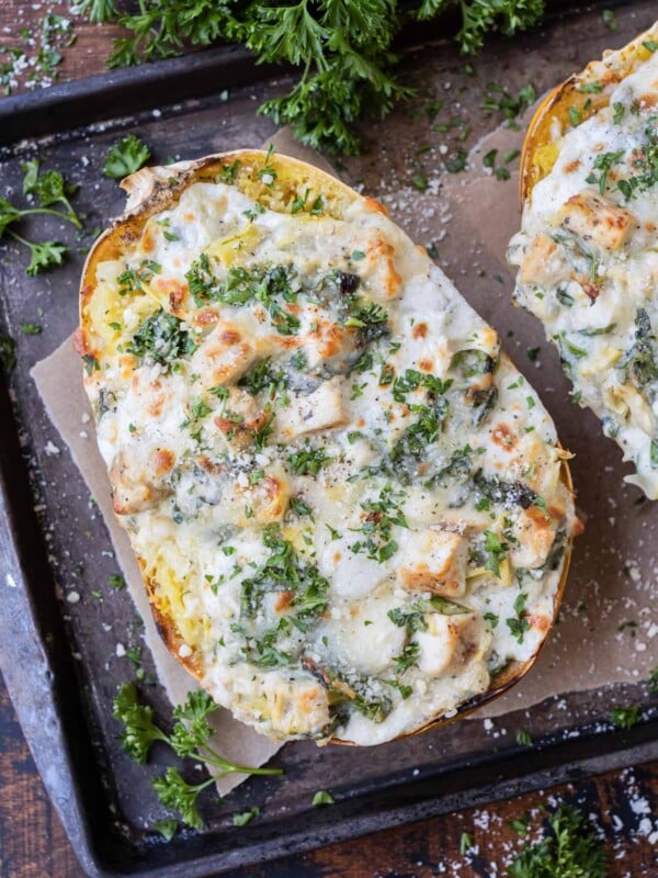 A baked spaghetti squash is stuffed with spinach, artichoke, and chicken with a creamy cheese sauce.