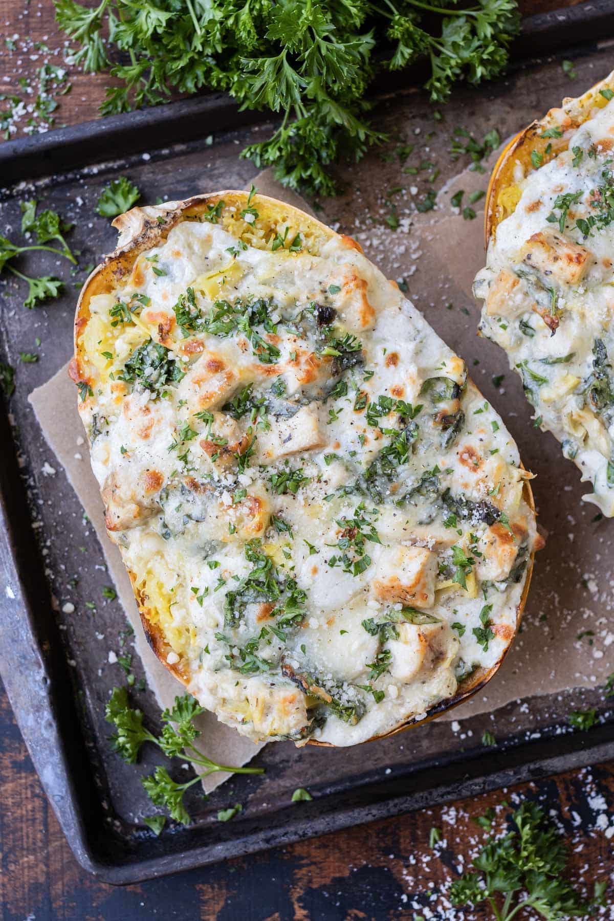 A baked spaghetti squash is stuffed with spinach, artichoke, and chicken with a creamy cheese sauce.