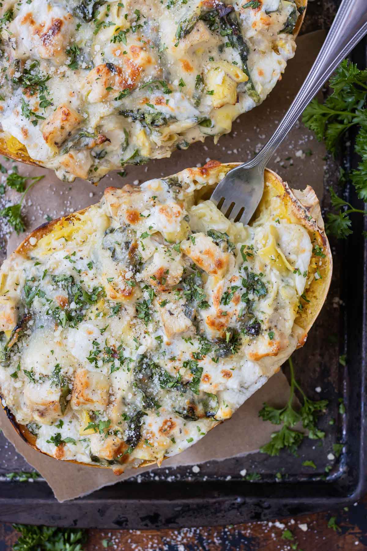 Baked spaghetti squash is filled with a decadent spinach artichoke filling and topped with chicken.