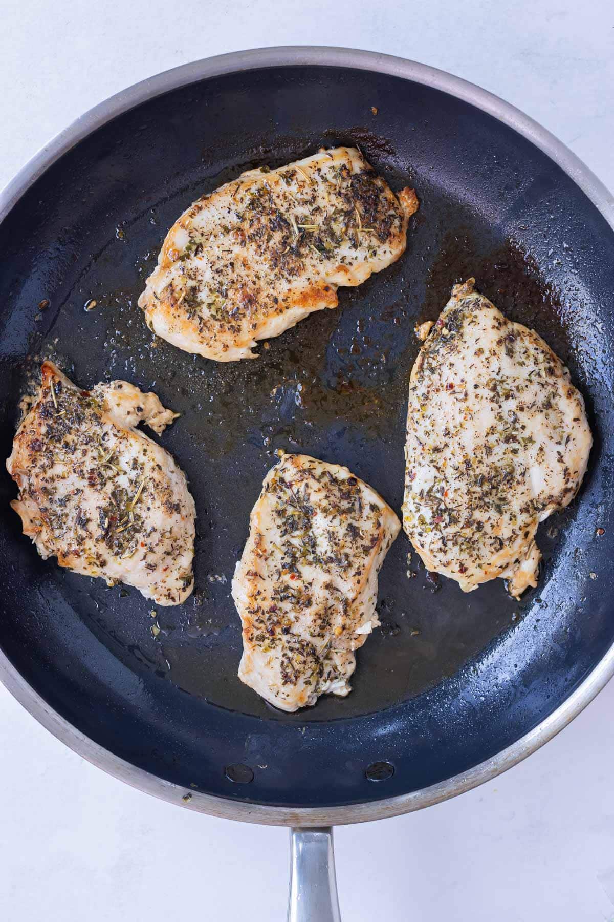 Seasoned chicken breasts are cook in a skillet.