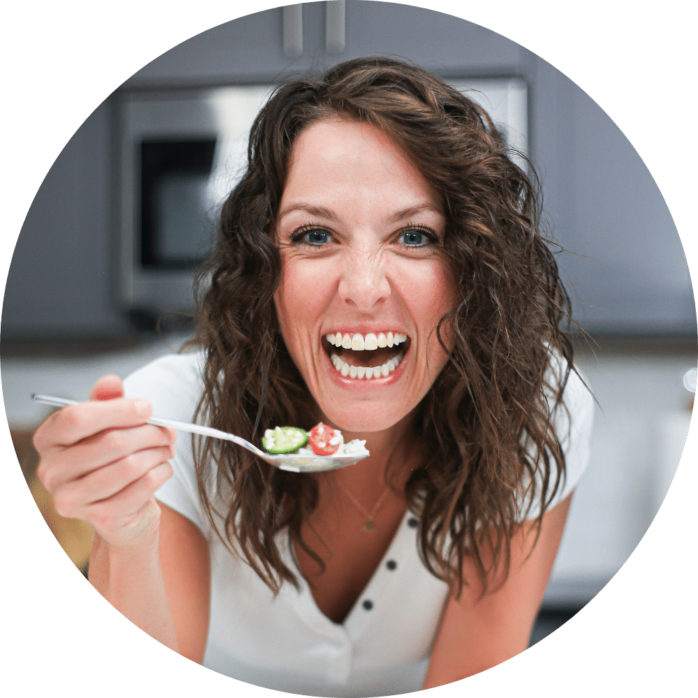 A photo of London Brazil, the author of the food blog Evolving Table, eating a bite of food in her kitchen.