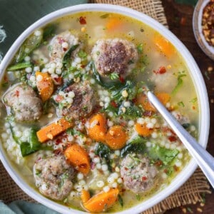 A metal spoon is shown in a bowl of healthy Italian wedding soup.