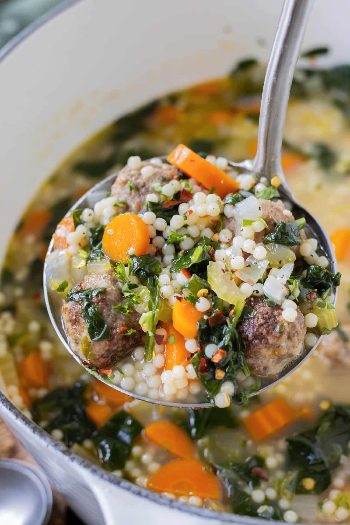 A ladle is used to serve the Italian wedding soup.