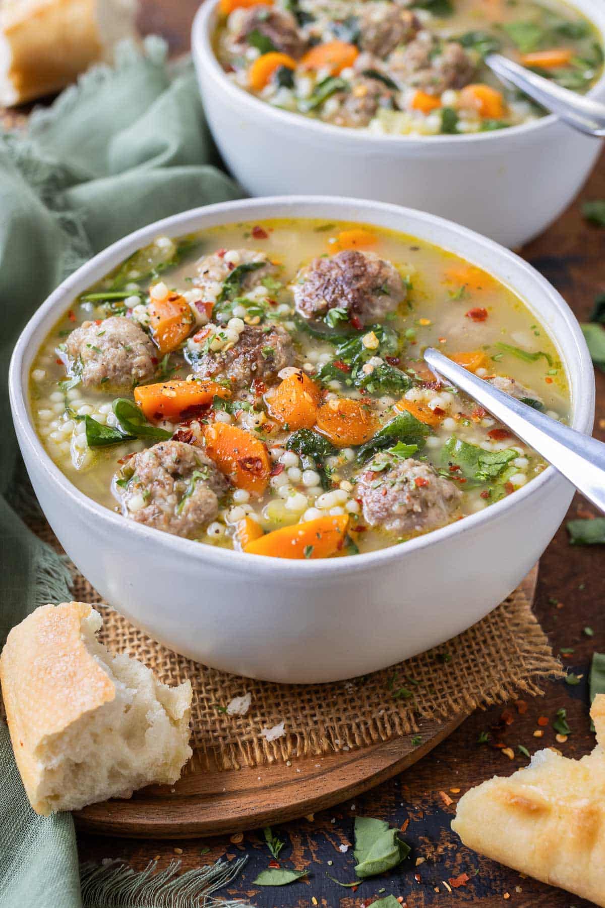 A metal spoon is shown in a bowl of healthy Italian wedding soup.