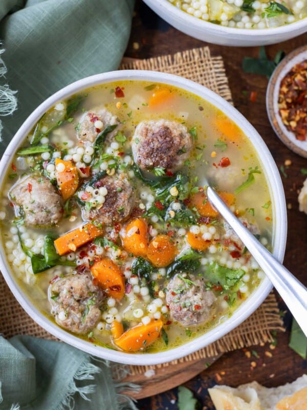 A metal spoon is shown in a bowl of healthy Italian wedding soup.