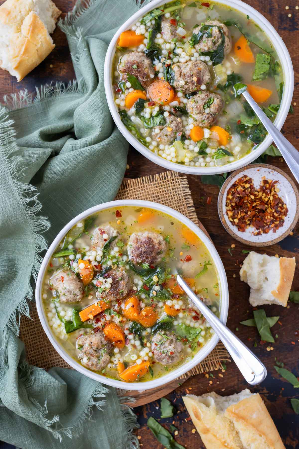 Comforting Italian wedding soup is served in a white bowl.