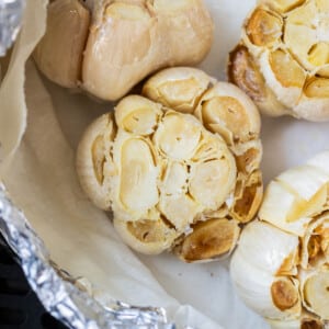 A packet full of air fryer roasted garlic heads with caramelized cloves.