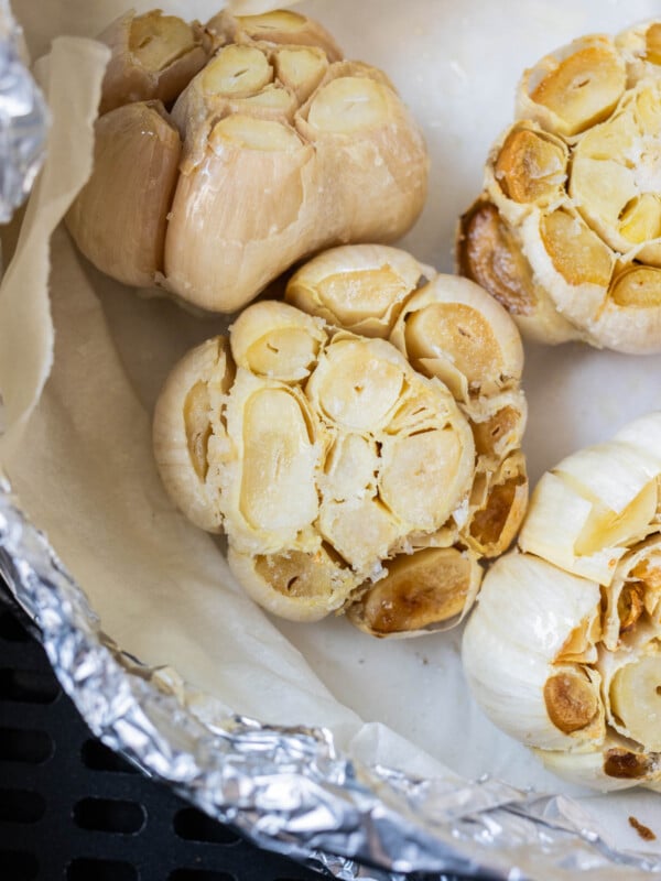 A packet full of air fryer roasted garlic heads with caramelized cloves.