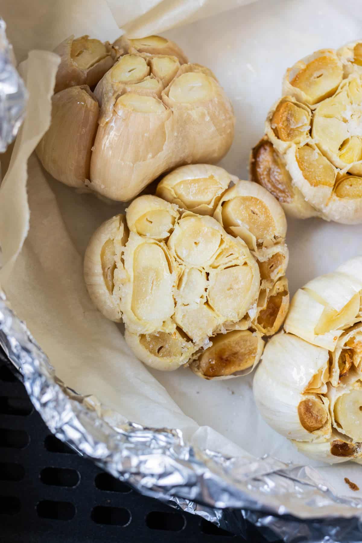 A packet full of air fryer roasted garlic heads with caramelized cloves.