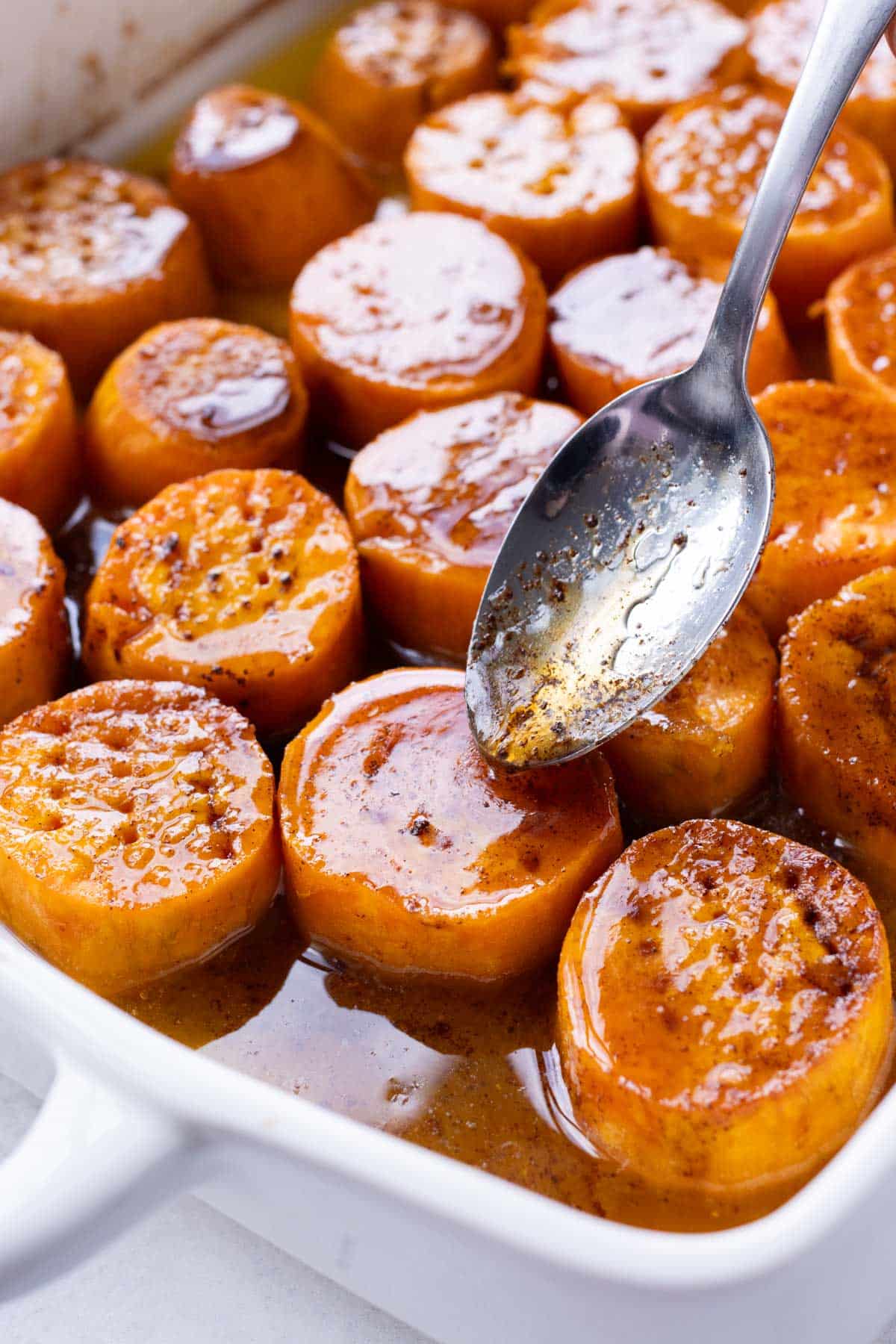 A spoon drizzles the maple sauce over the potatoes.