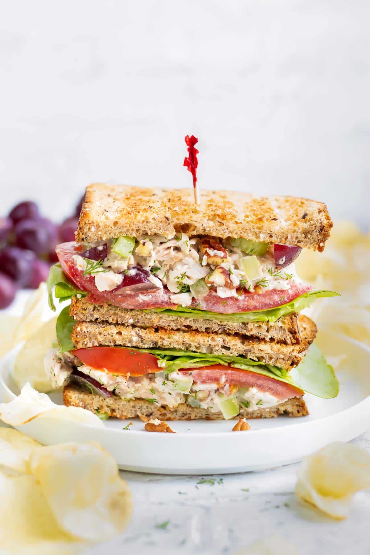 A turkey salad sandwich is sliced in half and stacked on a plate.