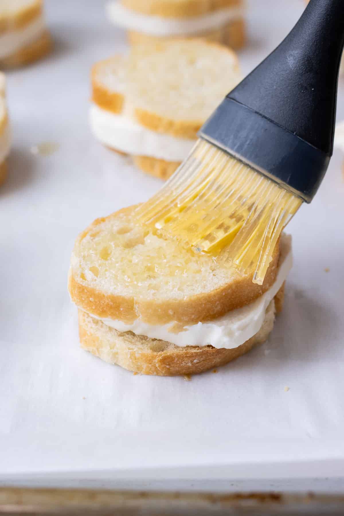 Butter is brushed onto a Mozzarella toast sandwich.