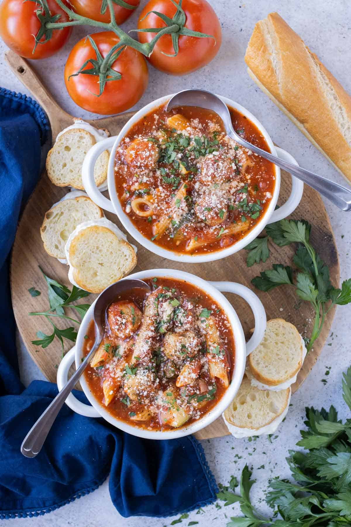 Two bowls have large servings of soup made with chicken Parmesan meatballs and fresh veggies.