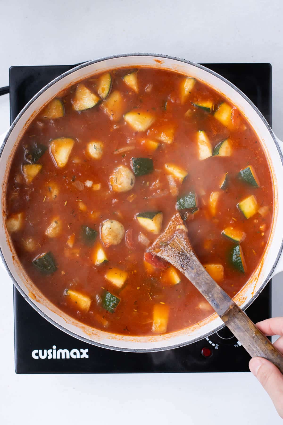 Noodles and meatballs are stirred into the pot.