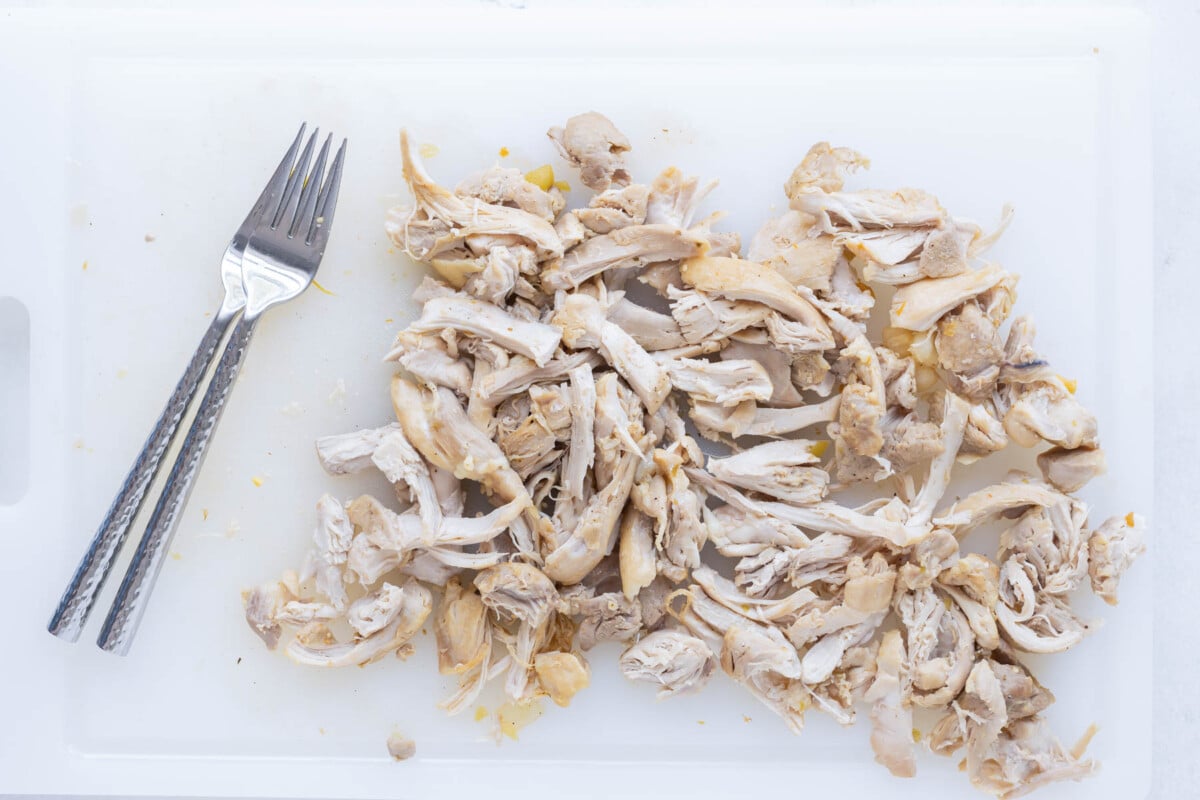 Chicken is shredded on a cutting board.