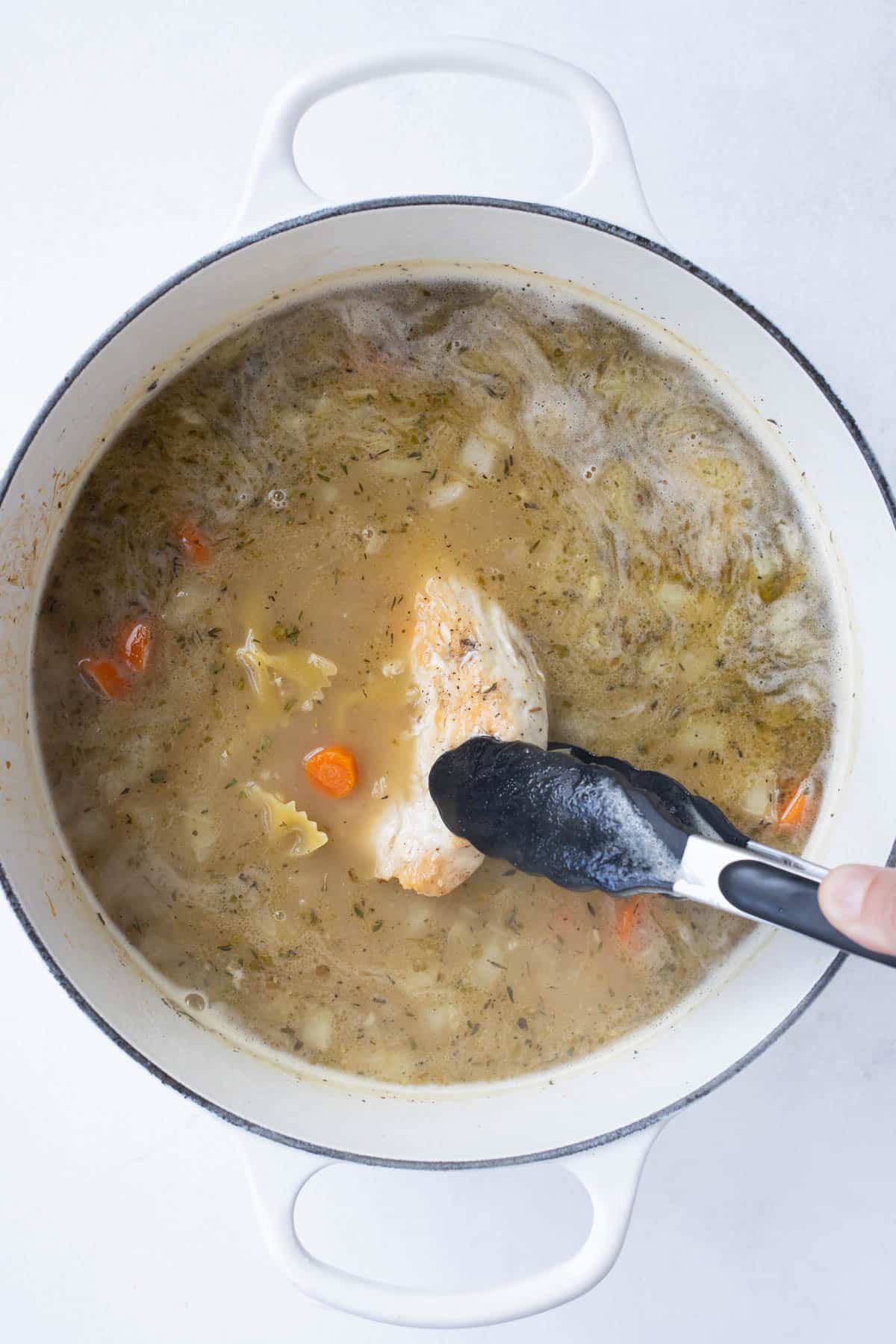 Chicken, veggies, and seasonings are added to the pot.