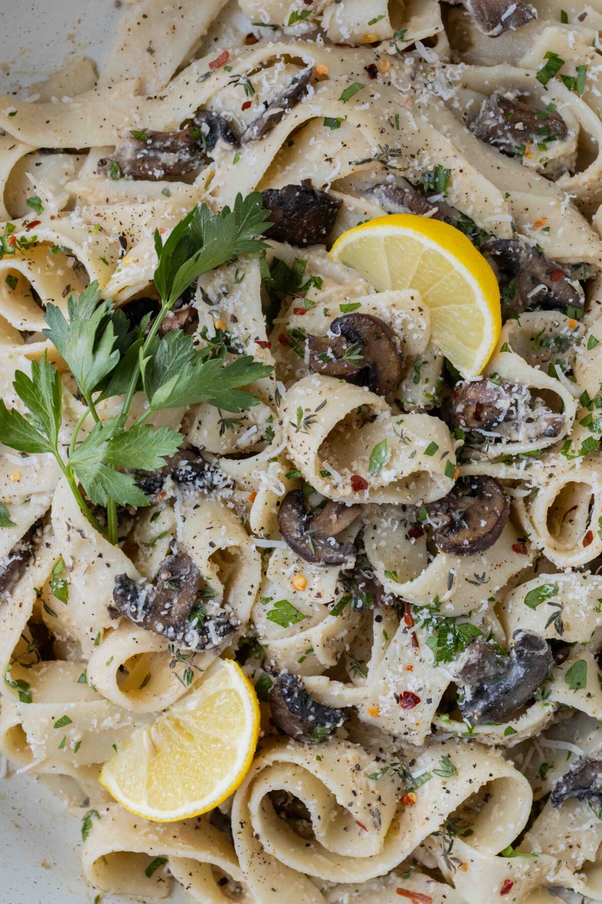 Lemon and parsley garnish a bowl of mushroom pappardelle pasta.