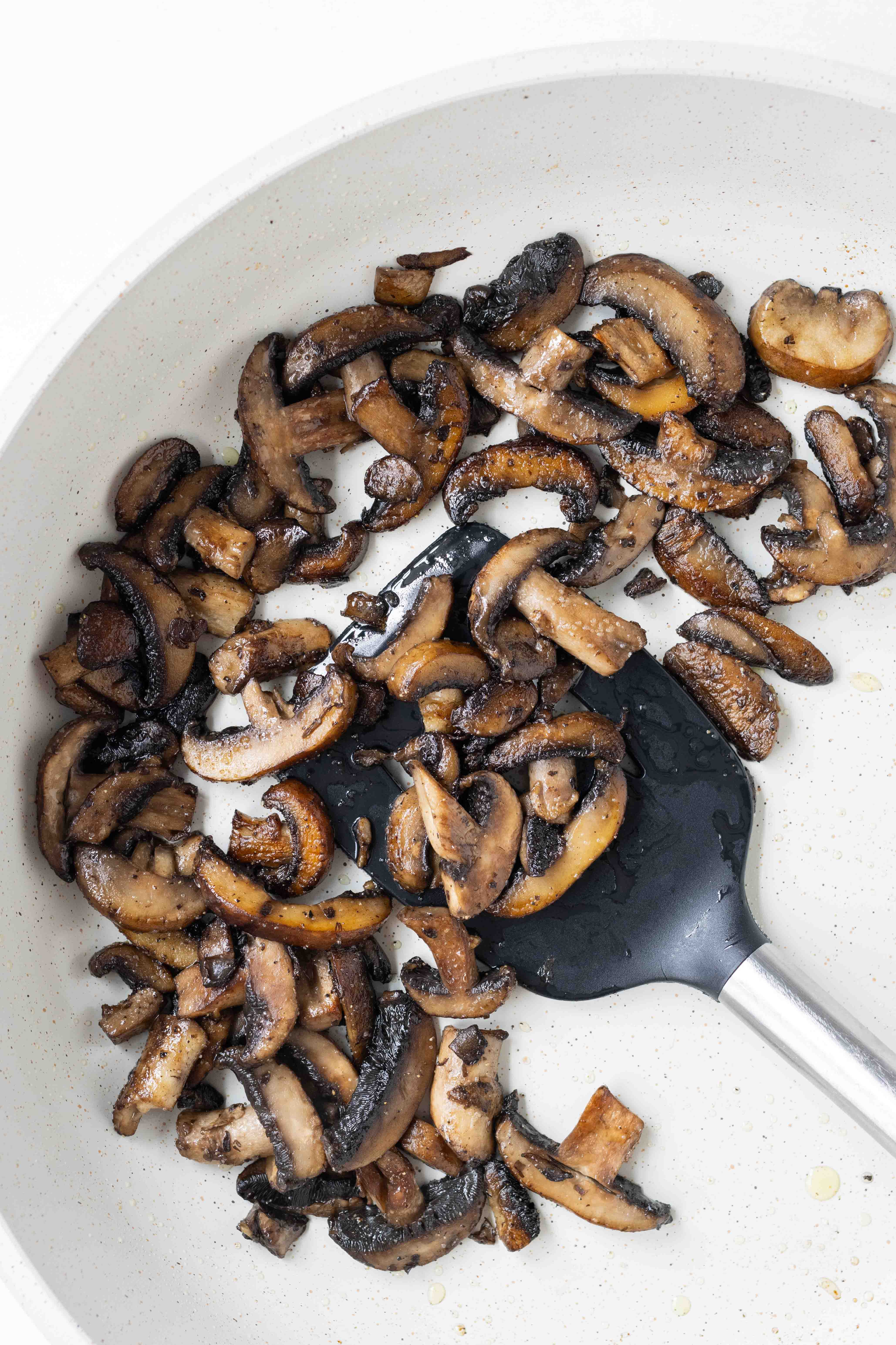 Mushrooms are sautéed in a skillet.