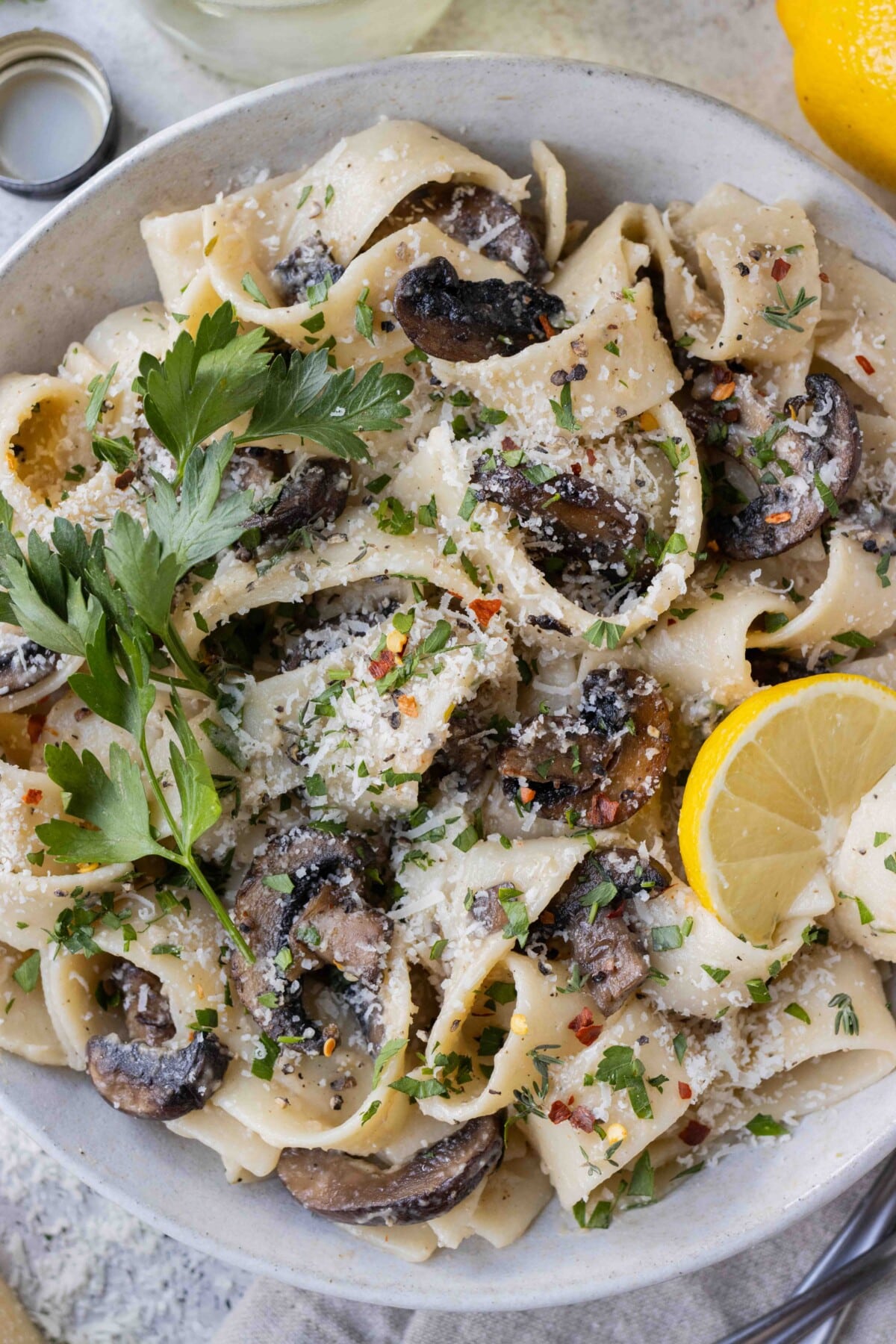 A bowl of mushroom pappardelle garnished with lemon and parsley.