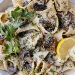 A bowl of mushroom pappardelle garnished with lemon and parsley.