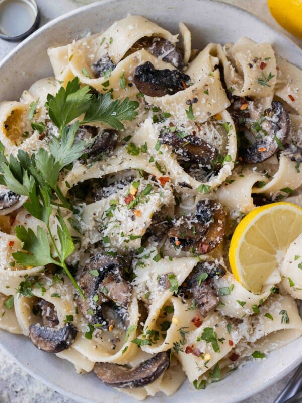 A bowl of mushroom pappardelle garnished with lemon and parsley.