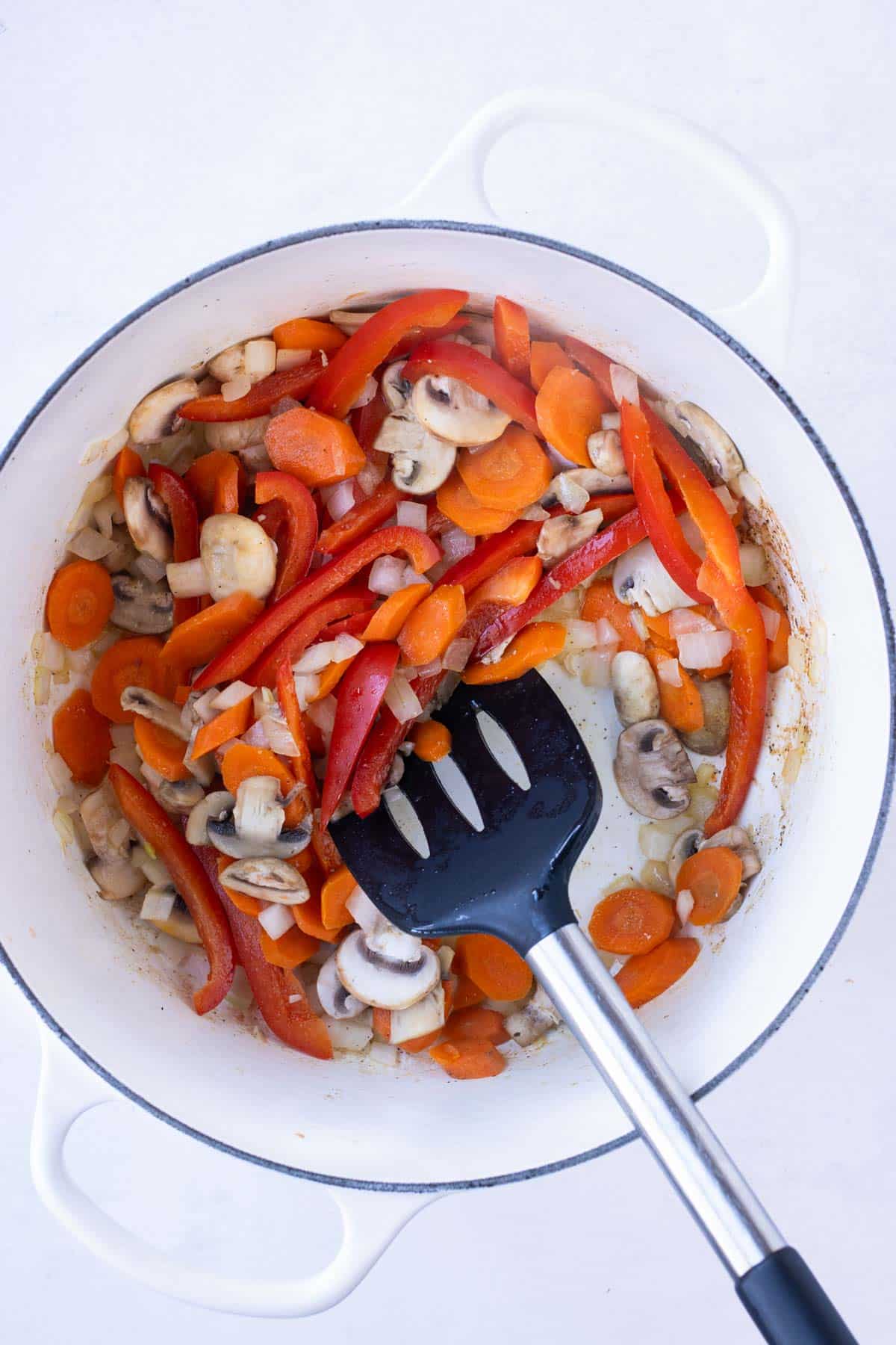 Sliced veggies are cooked in a large pot.