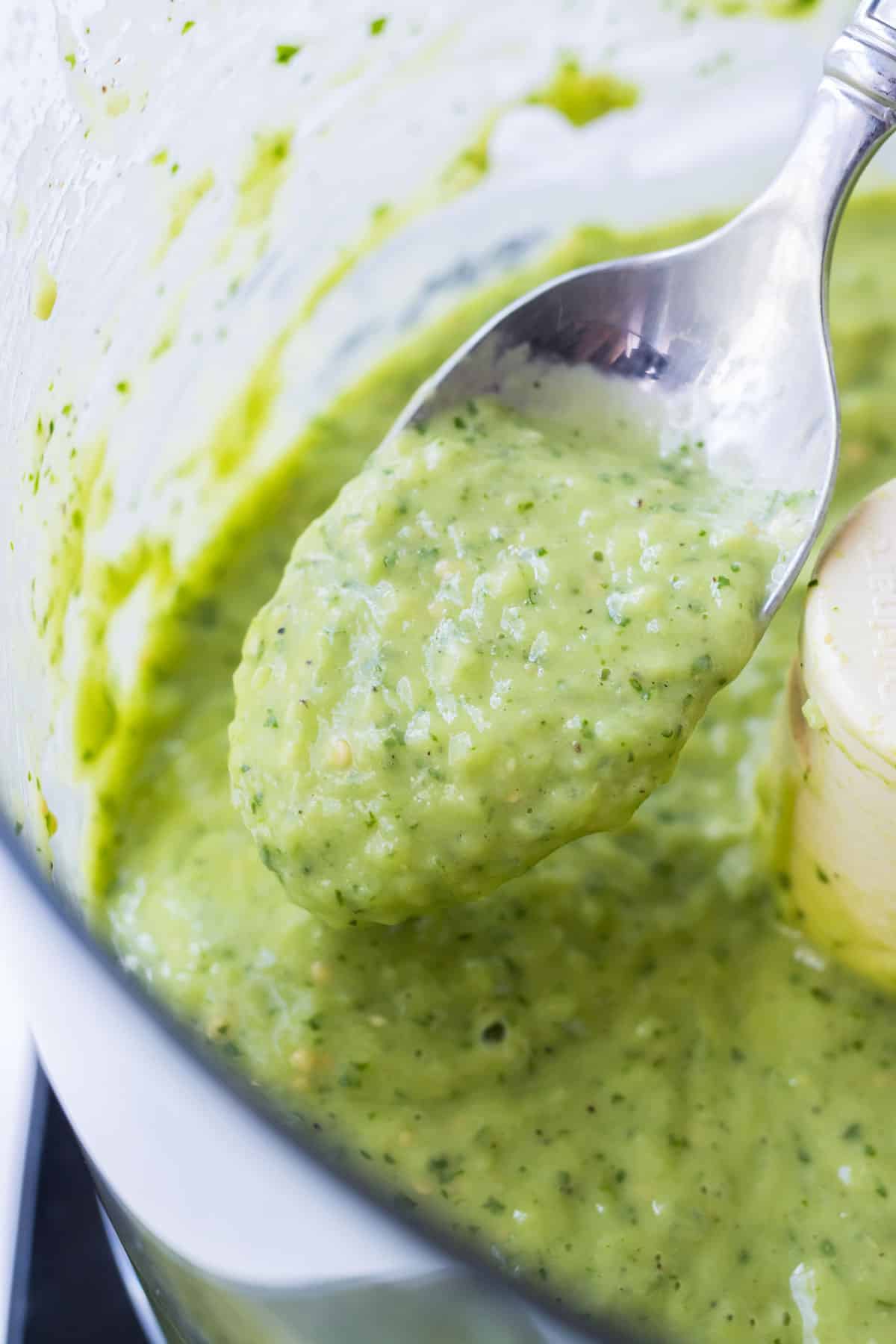 A spoon scoops up some avocado salsa verde to show the smooth consistency.