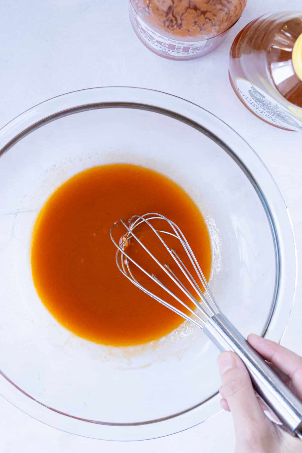 Homemade buffalo sauce is stirred in a bowl.