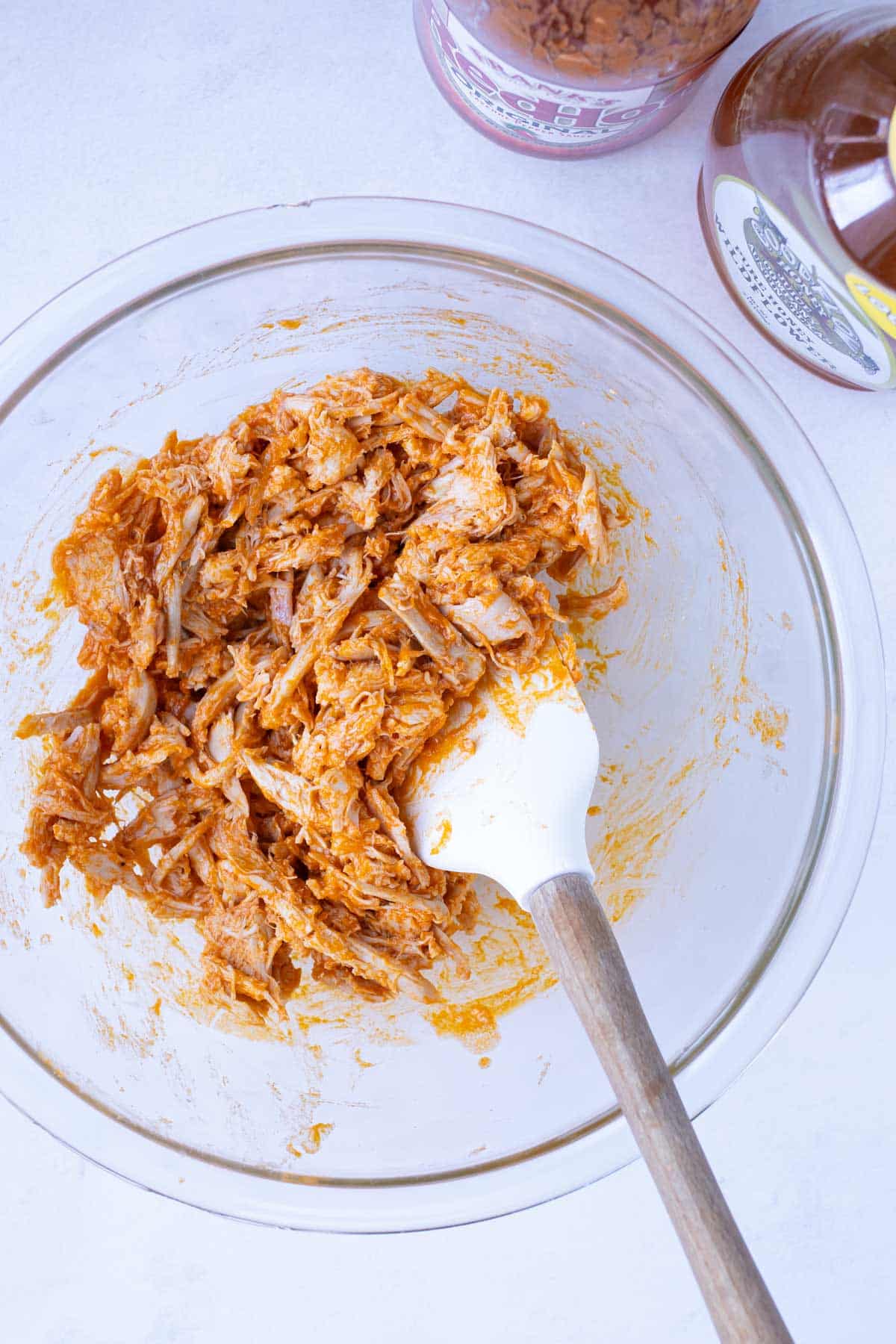 Shredded chicken is mixed with buffalo sauce.