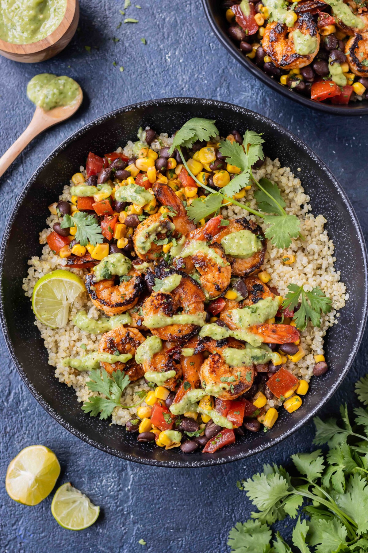 Chili lime shrimp quinoa bowls with an avocado salsa verde are served with fresh cilantro.