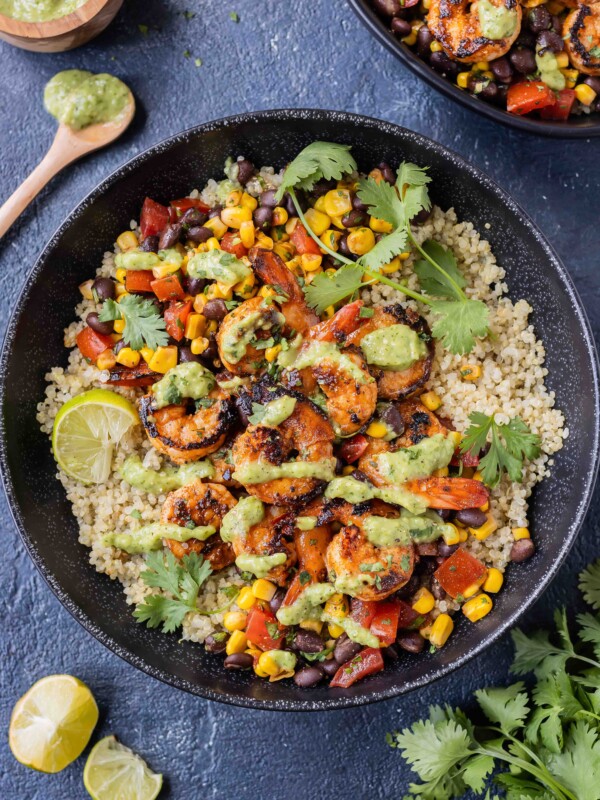 Chili lime shrimp quinoa bowls with an avocado salsa verde are served with fresh cilantro.