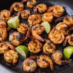 Chili garlic lime shrimp are cooked in a cast iron skillet.