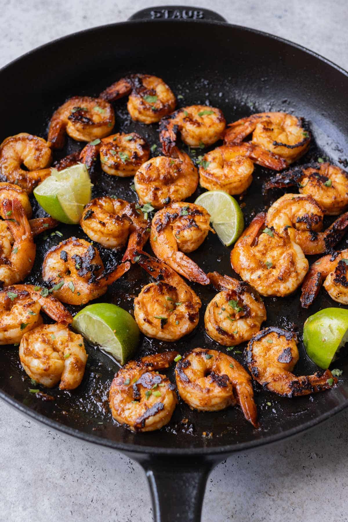 Chili garlic lime shrimp are cooked in a cast iron skillet.