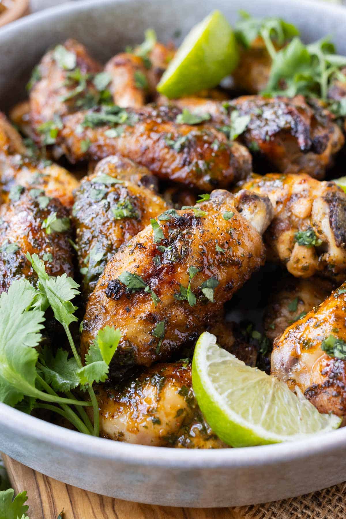 Cilantro lime wings are served with fresh lime wedges.