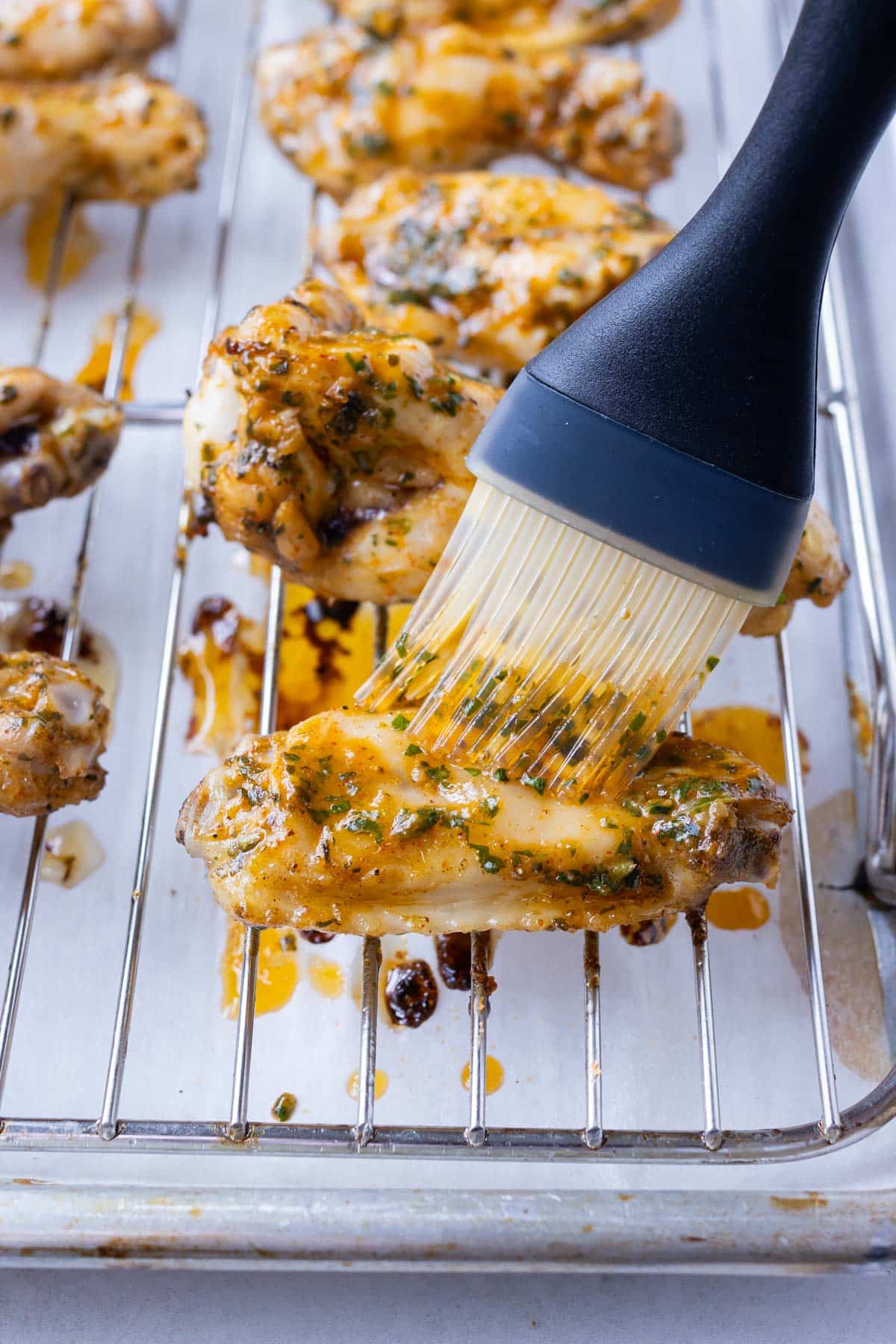 Sauce is basted onto wings in the oven.