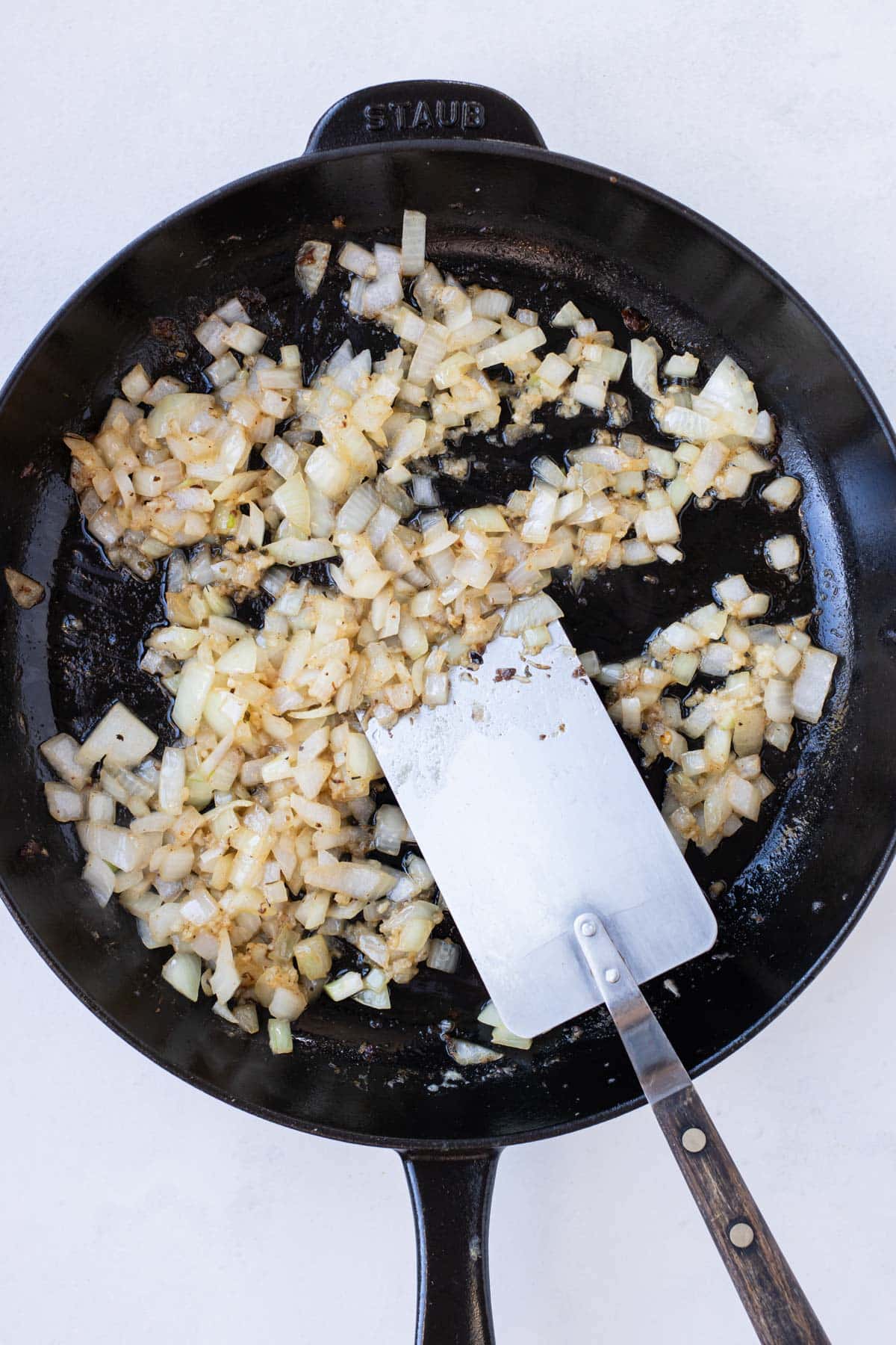 Onion and garlic are cooked in a skillet.