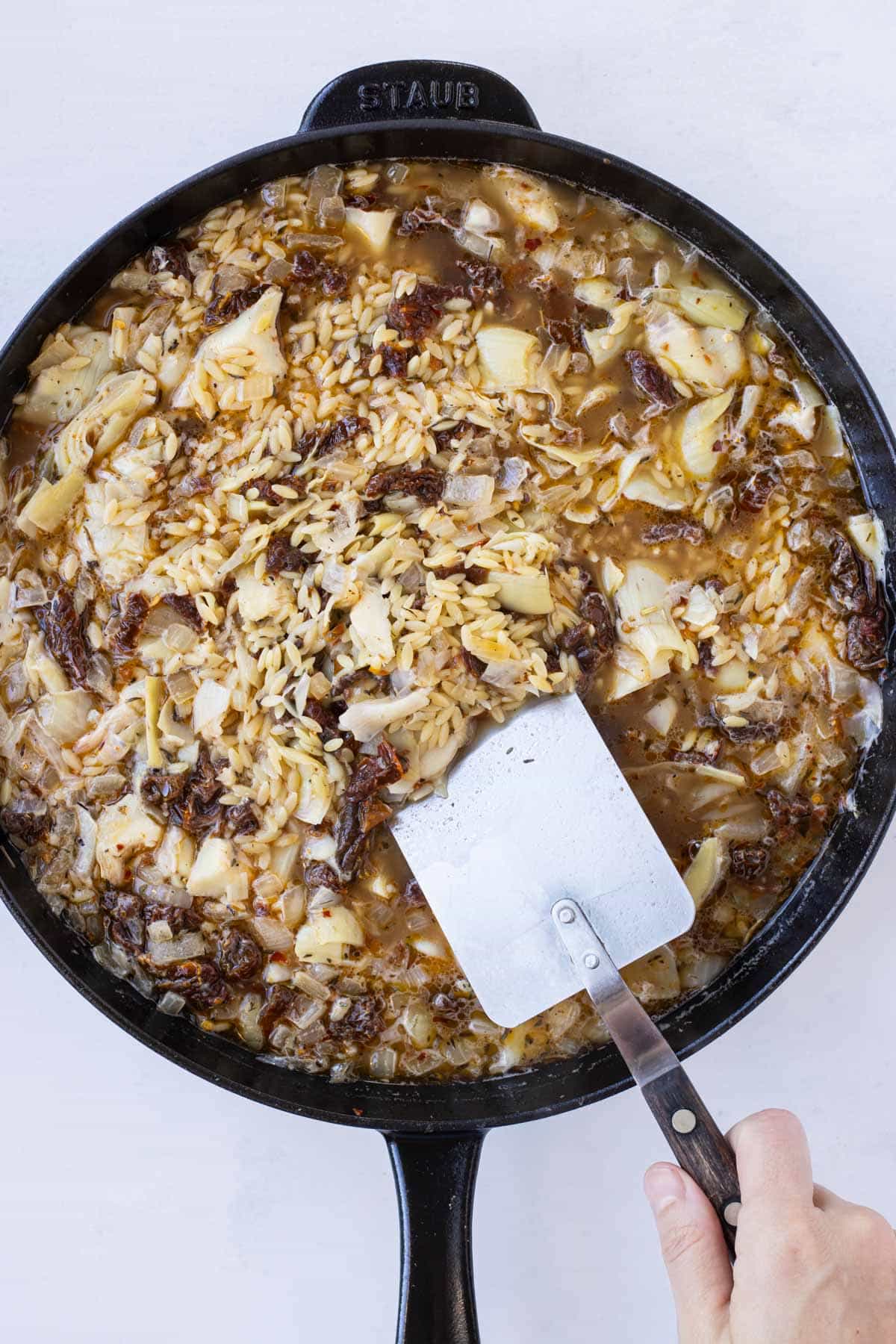 Broth and artichokes are added to the skillet.