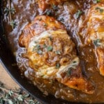 French onion chicken in a cast iron skillet with caramelized onions, gruyere cheese, and fresh thyme on top.