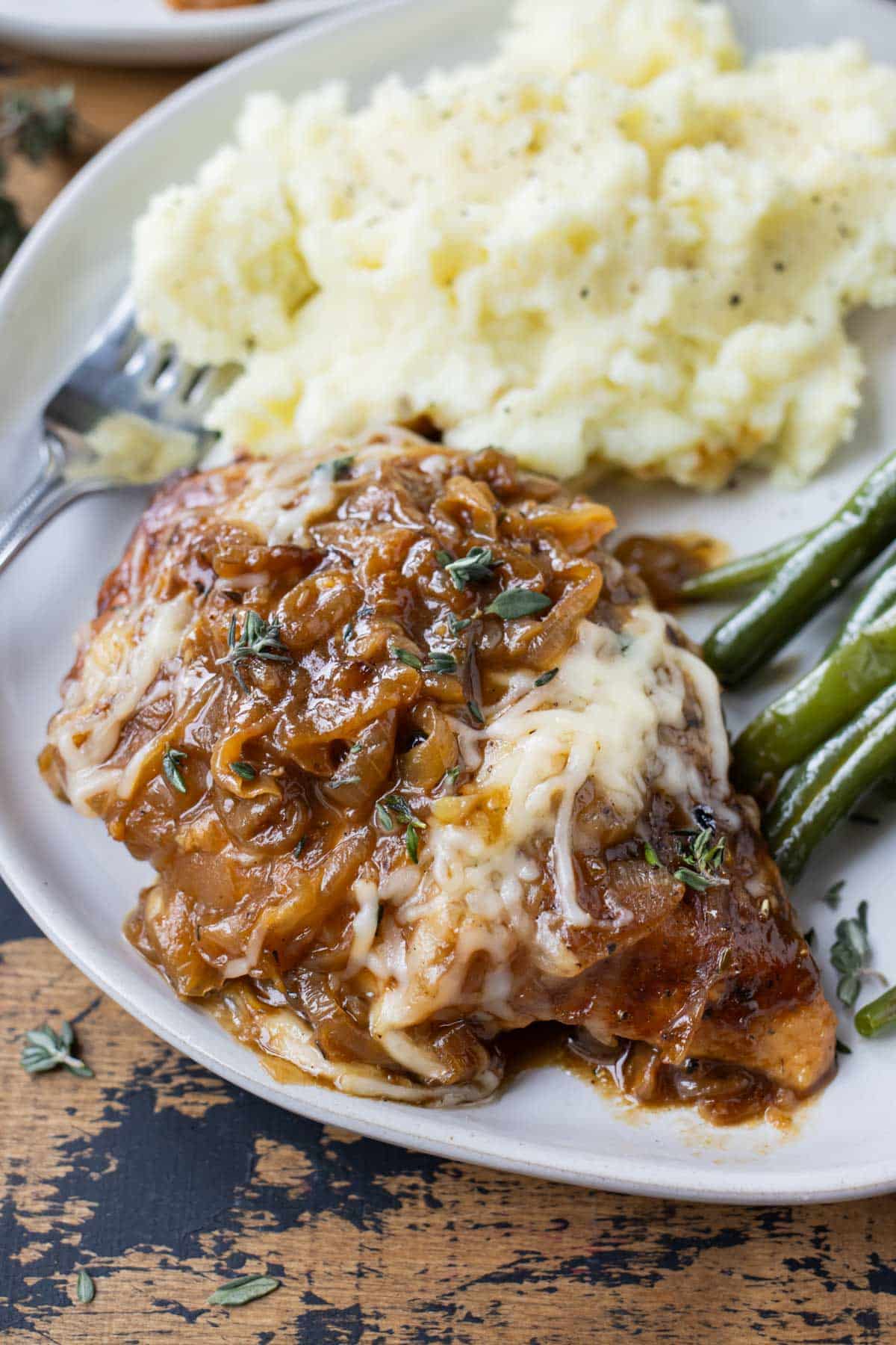 French onion chicken is served alongside mashed potatoes and green beans.