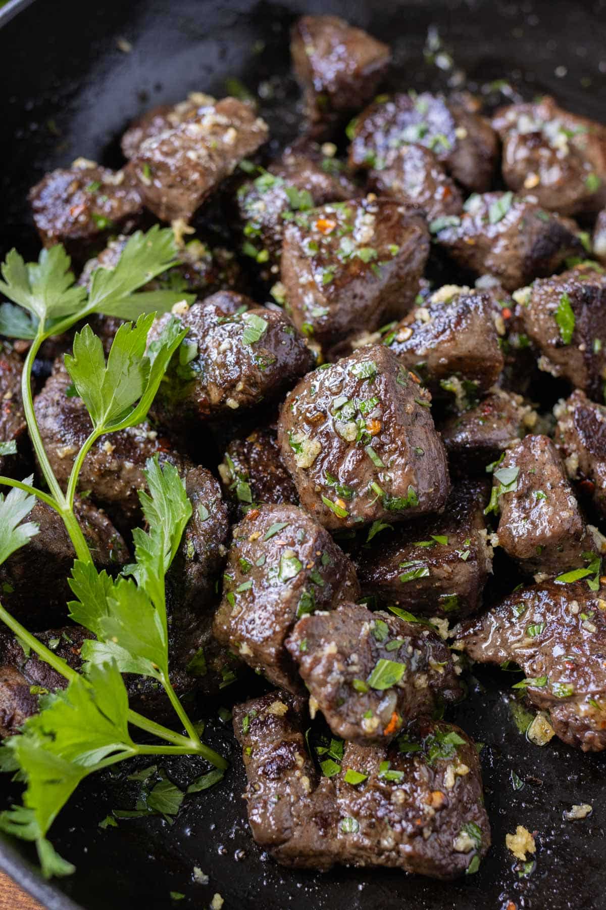 Garlic butter steak bites are quickly cooked in a skillet on the stove.