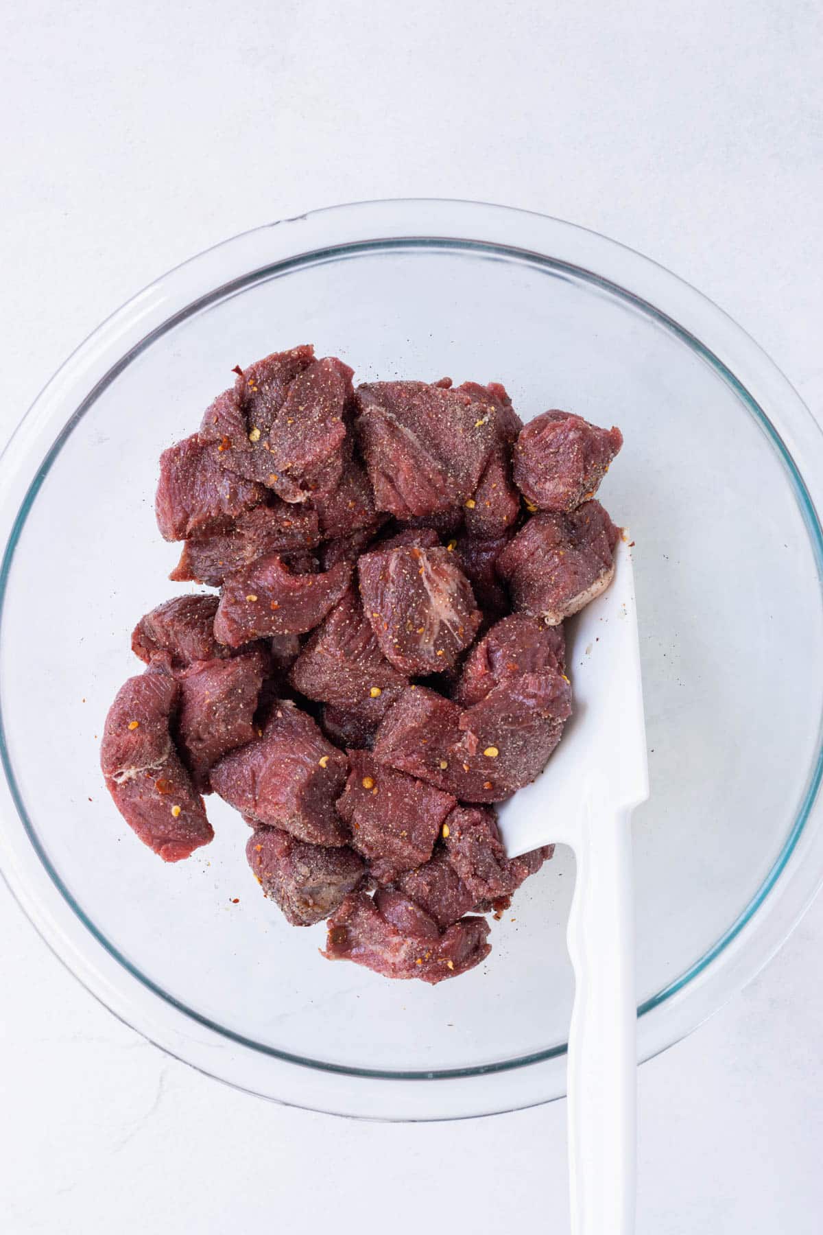 Cubed steak is seasoned in a bowl.