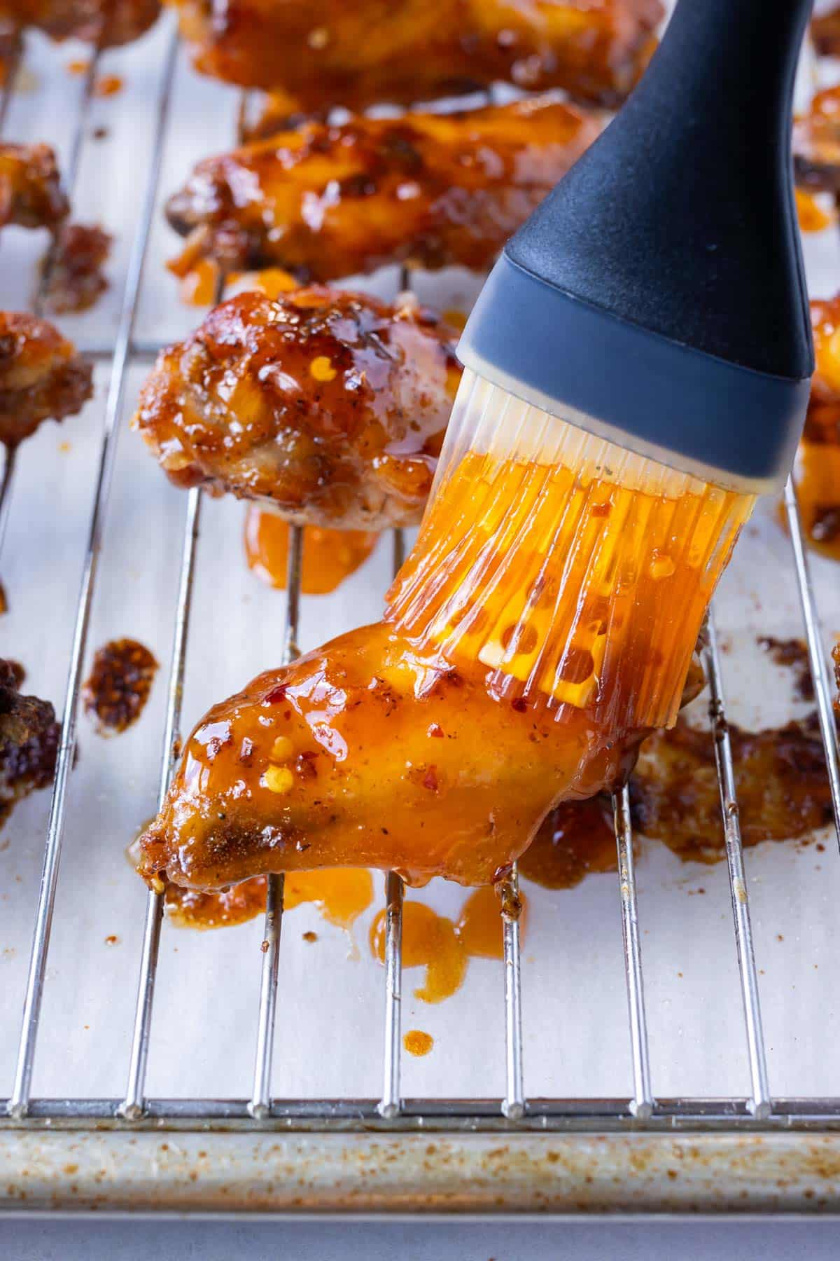 Sauce is brushed on baked chicken wings.