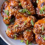 Hot honey chicken wings are stacked in a white bowl for an easy appetizer.