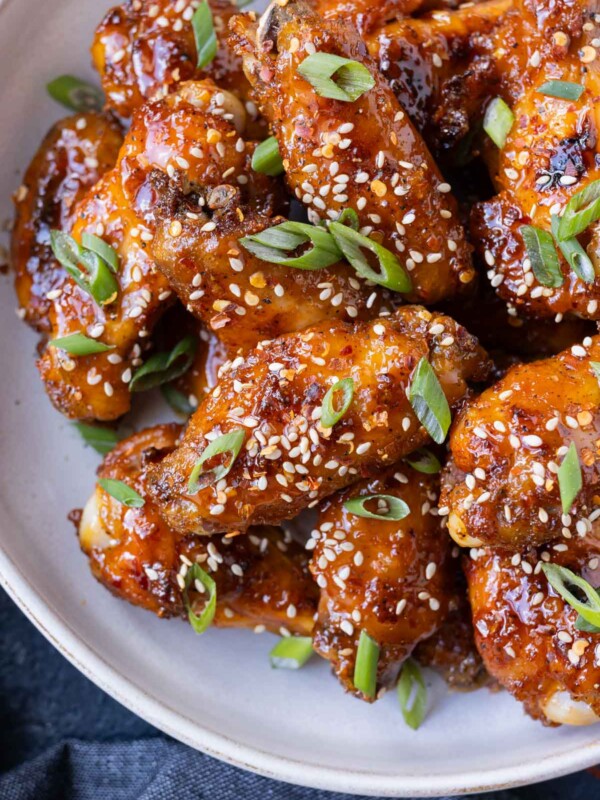 Hot honey chicken wings are stacked in a white bowl for an easy appetizer.